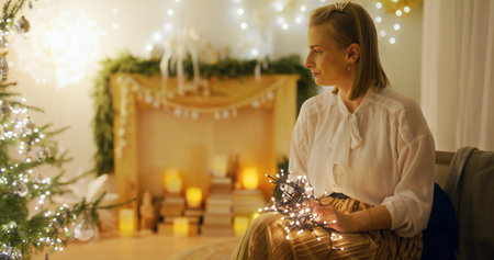 Woman Arranges Christmas Decorations and Untangles Lights at Homeの写真素材