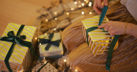 Woman Ties a Ribbon on a Present Wrapping It