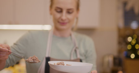 Woman puts meat into meat grinder and prepares holiday dishesの写真素材
