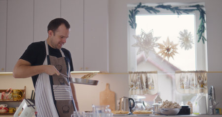 Smiling Man Flipping Pancakes in Pan While Working in Kitchenの写真素材