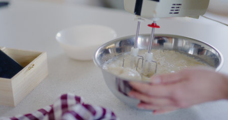 Woman Using Mixer and Mixing Pancake Batter in Bowlの写真素材