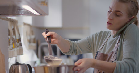Busy Woman in Kitchen Talking on Phone While Preparing Food and Fryingの写真素材