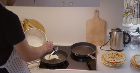 Man Pours Pancake Batter in Pan and Fry Pancakesの写真素材