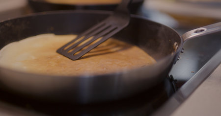 Close-Up of Hand Touching Pancake in Pan While Bakingの写真素材