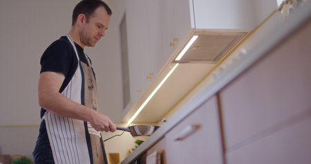 Man Flips Pancake in Pan While Working in Kitchenの写真素材