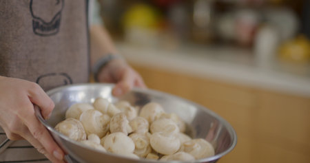 Woman shaking fresh mushrooms in a metal bowlの写真素材