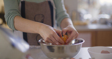 Close-up of cracking raw egg into bowl preparing dough