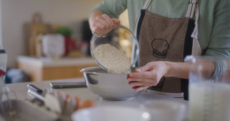 Chef pours flour into bowl prepares doughの写真素材