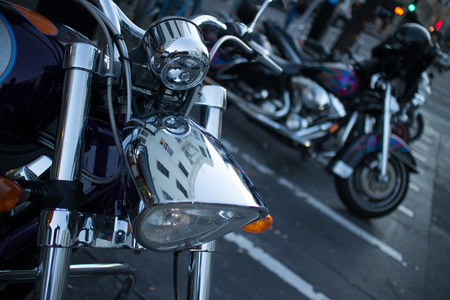 Detail of a shiny chrome headlamp on a cruiser style motorcycle, seen at dusk in North Beach, San Francisco, California.の写真素材