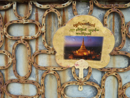 A rusty steel grille reinforces a door in Yangon Rangoon, myanmar Burma. Rusty water patterns have formed behind the grille, which is now adorned with a hand fan depicting the famous and holy Shwedagon Pagoda.の写真素材