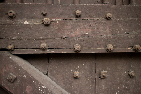 Close up of a heavy wooden door of a temple in Asiastudded with bolts; crossbeams and slats form a diagonal patternの写真素材