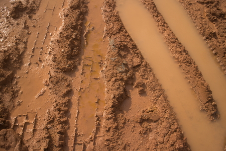 Close up of muddy vehicle and tire tracks filled with water on a construction site, featuring...