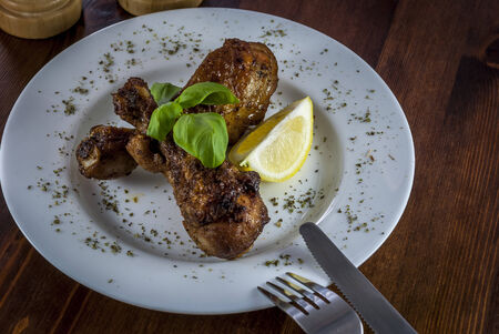 grill chicken with vegetables and cutlery and basil on white plateの写真素材