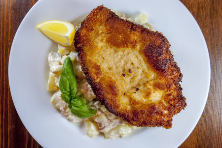 Wiener schnitzel with potato and vegetables salad on wood tableの写真素材