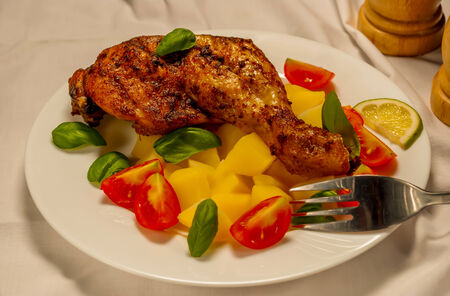 grill chicken thigh with potatoes on white plateの写真素材