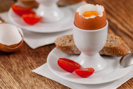 Soft boiled egg with baguette on wood table