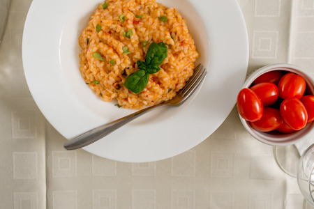 Red risotto with tomato and basil on white plateの写真素材