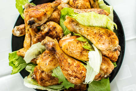 Grilled chicken legs and salad on black plateの写真素材