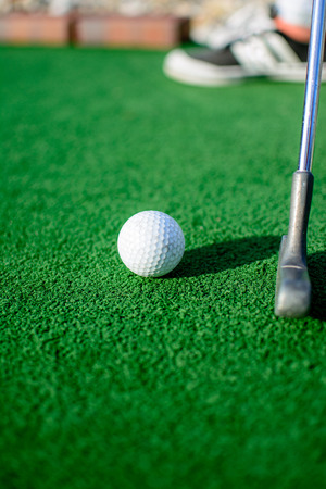 White golf ball on green grass in sunny day
