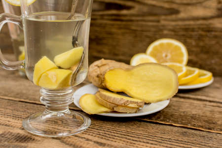 Hot ginger drink or beverage with lemon in glass cup on wood tableの写真素材