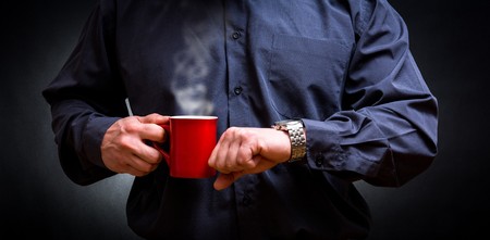 Business man with  newspaper drinking hot coffee and looking watchの写真素材
