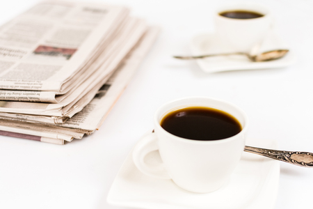 Newspaper and white cup of coffee on white backgroundの写真素材