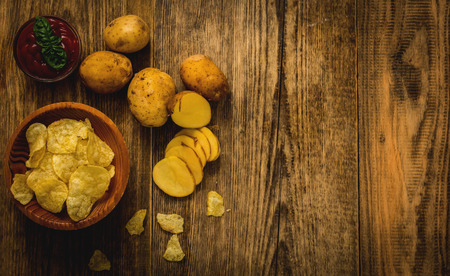 Salty potato chips snack with tomato dip on wood table top viewの写真素材