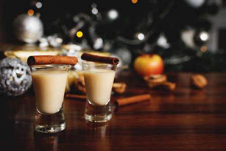 Traditional eggnog with cinnamon on wood table with christmas giftsの写真素材