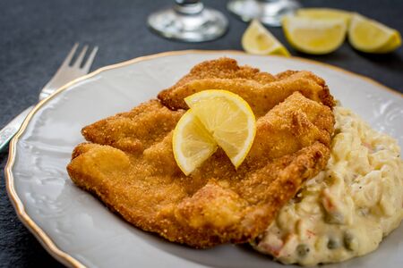 Pork fried schnitzel with traditional potato salad on black stone tableの写真素材