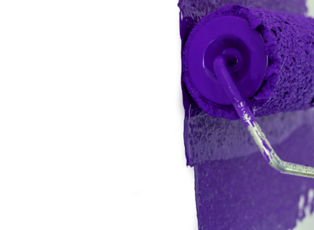 Woman painting wall in purple with rollerの写真素材