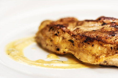 Grelled pork chop steak on white dish on white backgroundの写真素材