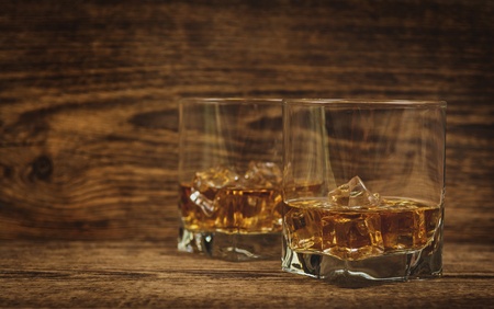 Whisky or whiskey or bourbon with ice on wood backgroundの写真素材