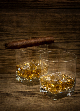 Whisky or whiskey or bourbon with ice and cigar  on wood backgroundの写真素材