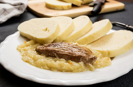 Traditional czech cuisine pork meat, dumpings and cabbage on dark stone tableの写真素材