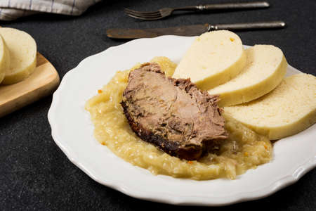 Traditional czech cuisine pork meat, dumpings and cabbage on dark stone tableの写真素材