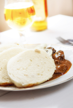 Traditional czech goulash with dumplings and beer on white tableの写真素材