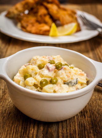 Traditional czech potato salad with mayonnaise and vegetables in white plateの写真素材