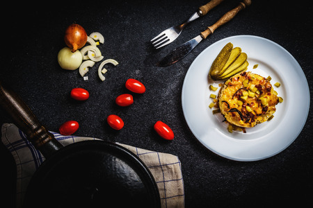 Gratin potatoes with onion and gherkin on white plate on black stone table with cherry tomatoes. Czech traditional cuisineの写真素材