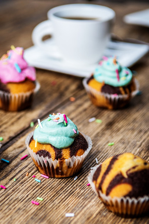 Chocolate cupcake with colored pink and green cream on wood tableの写真素材