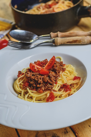 Traditional Italian pasta spaghetti bolognese with minced meat and  tomatoes on  wood tableの写真素材