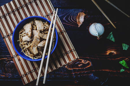 Traditional asian or chines noodles with chicken meat on bowl with chopsticks on wood table top viewの写真素材