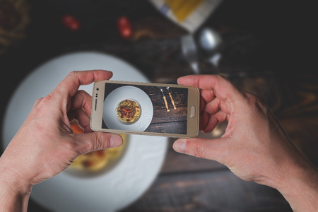 Man taking photo of Traditional Italian pasta spaghetti bolognese with minced meat and  tomatoes on dark wood table top viewの写真素材