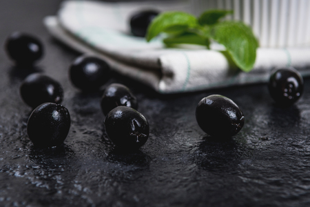 Black olives and basil leaves on black stone tableの写真素材