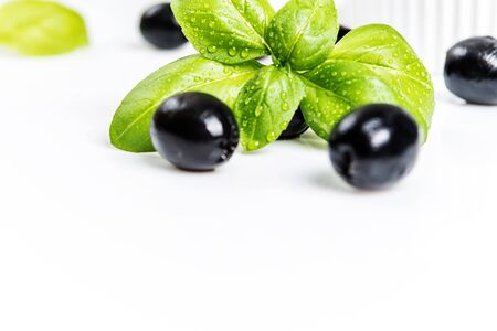 Black olives and basil leaves  on white backgroundの写真素材