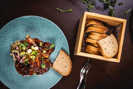 Pork rib in hoisin BBQ marinade with bread on blue plate