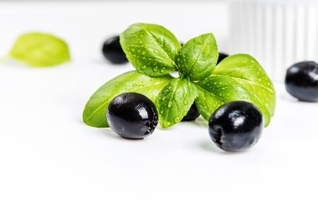 Black olives and basil leaves  on white backgroundの写真素材