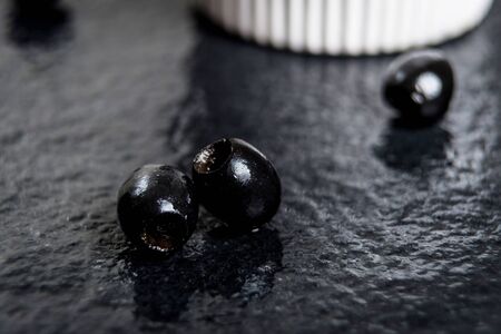 Black olives  on wet black stone tableの写真素材