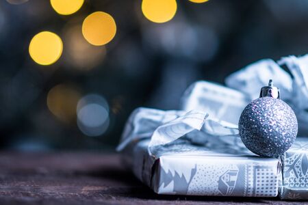 Christmas gifts in silver paper and silver bulbs on wood tableの写真素材