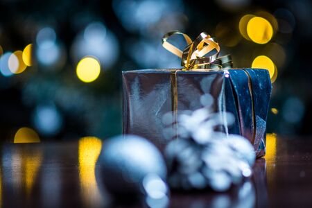 Christmas gifts in silver paper and silver bulbs on wood tableの写真素材