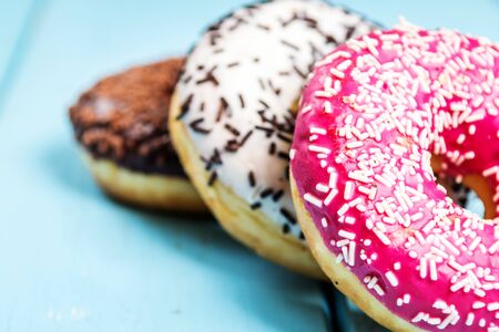 Chocolate, red, and white donuts and coffee on blue tableの写真素材